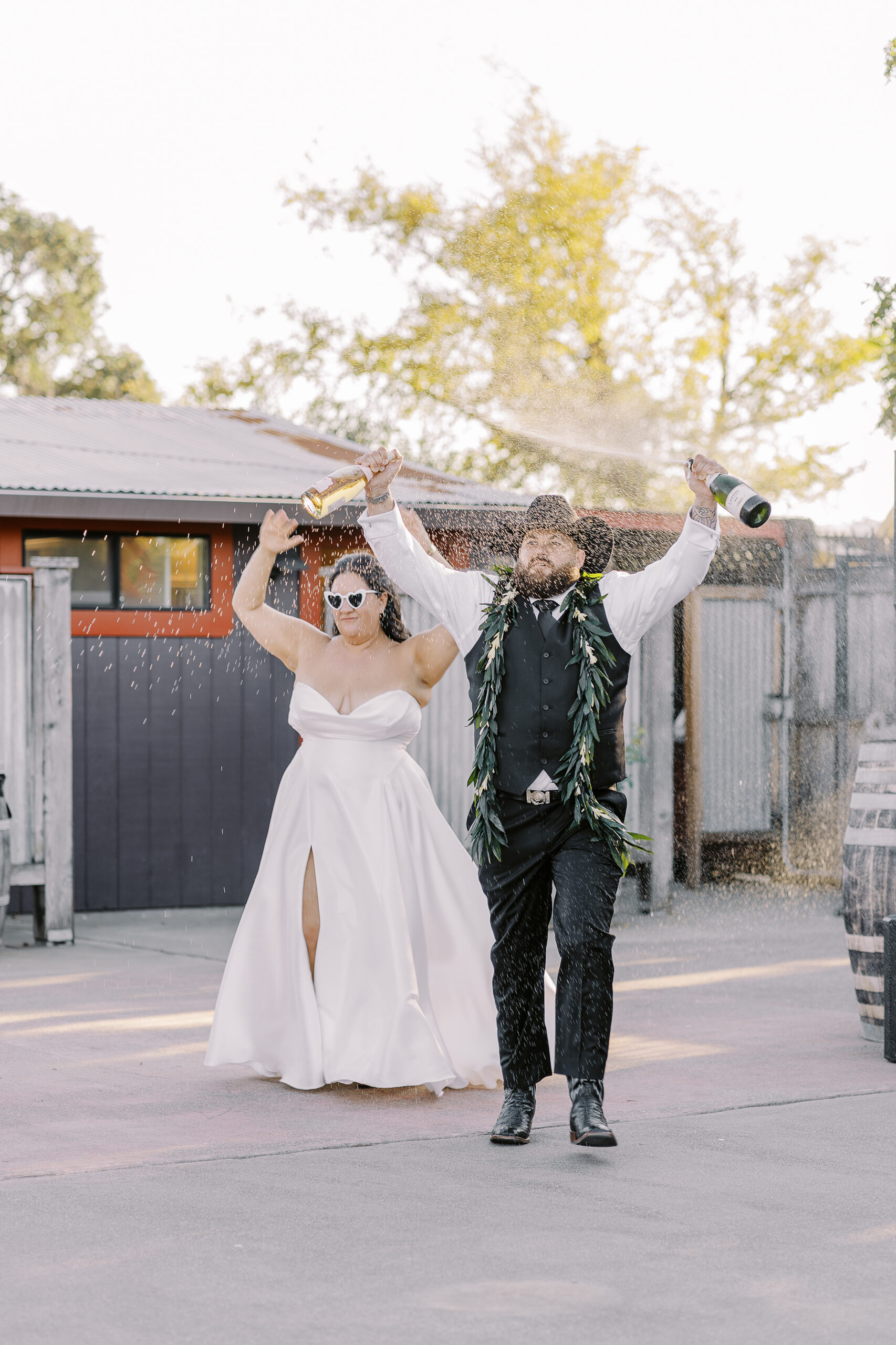 a bride and groom make their grand entrance to their reception by spraying champagne at their sonoma winery wedding.