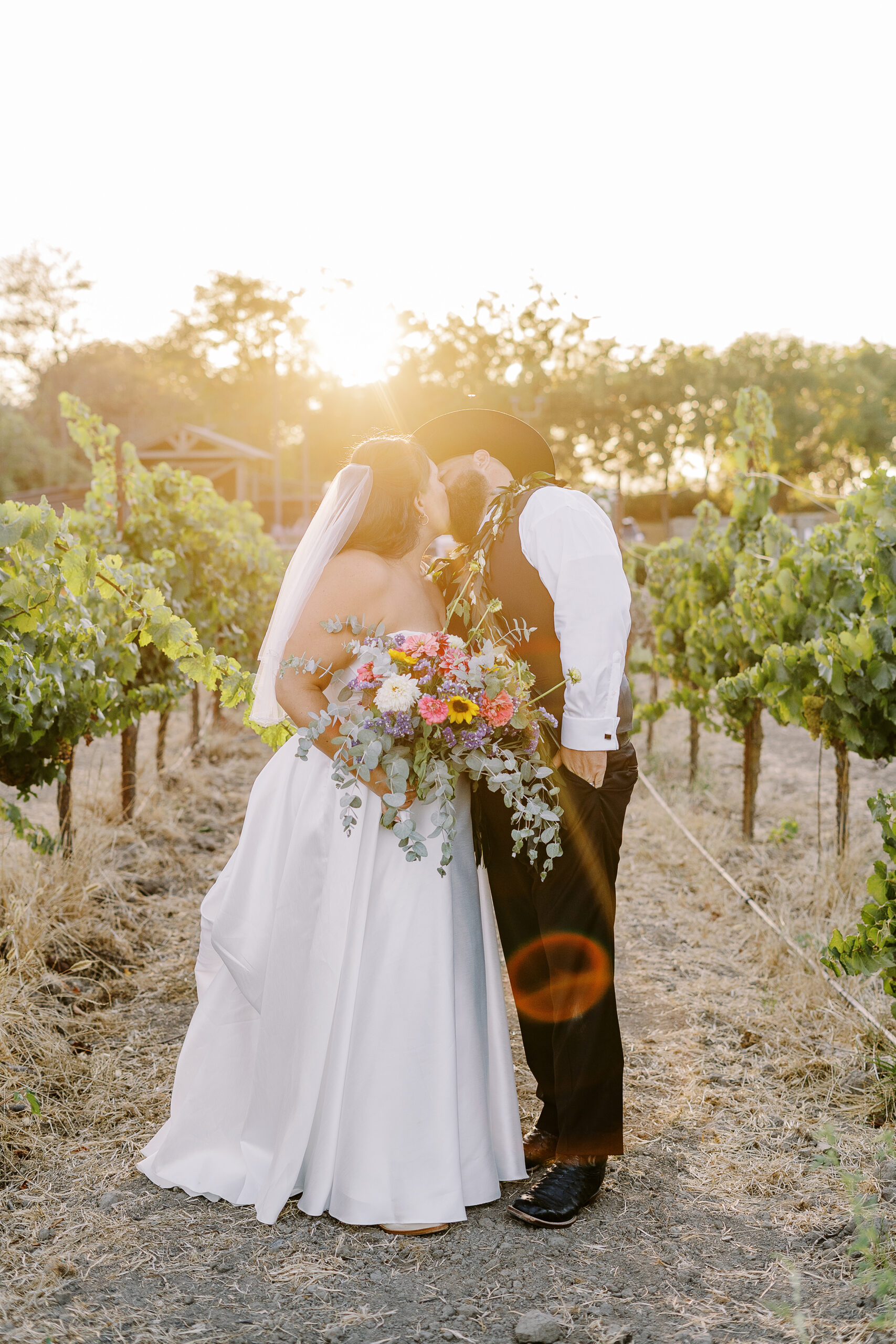 a bride and groom share kisses and pose for portraits at sunset at their sonoma winery wedding.
