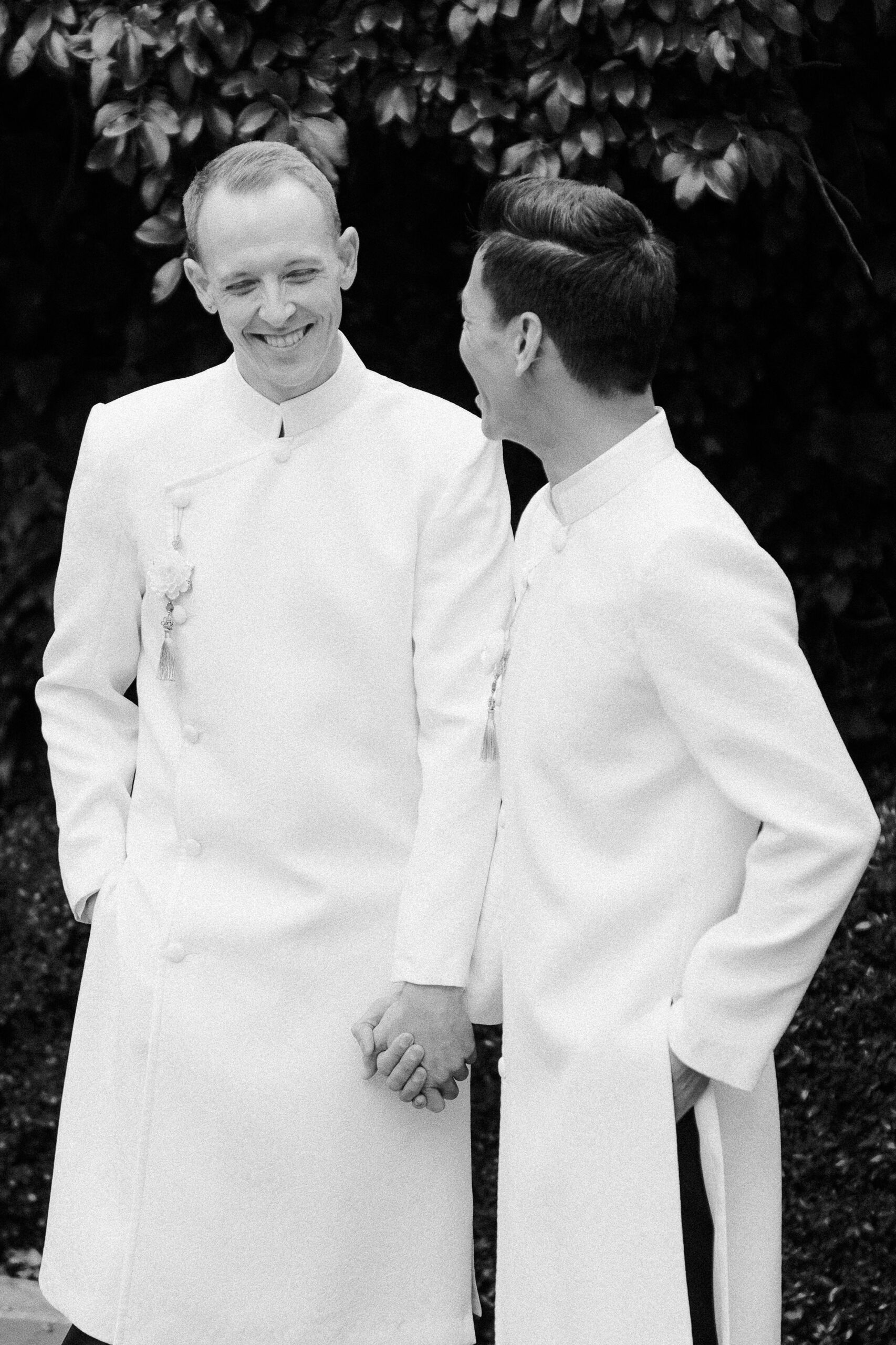 a black and white image of two grooms laughing together while holding hands at their Vizcaya Sacramento Wedding
