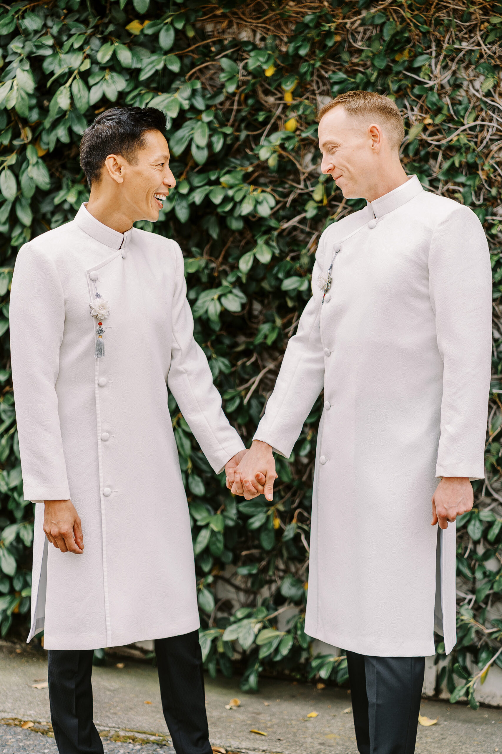 a black and white image of two grooms laughing together while holding hands at their Vizcaya Sacramento Wedding