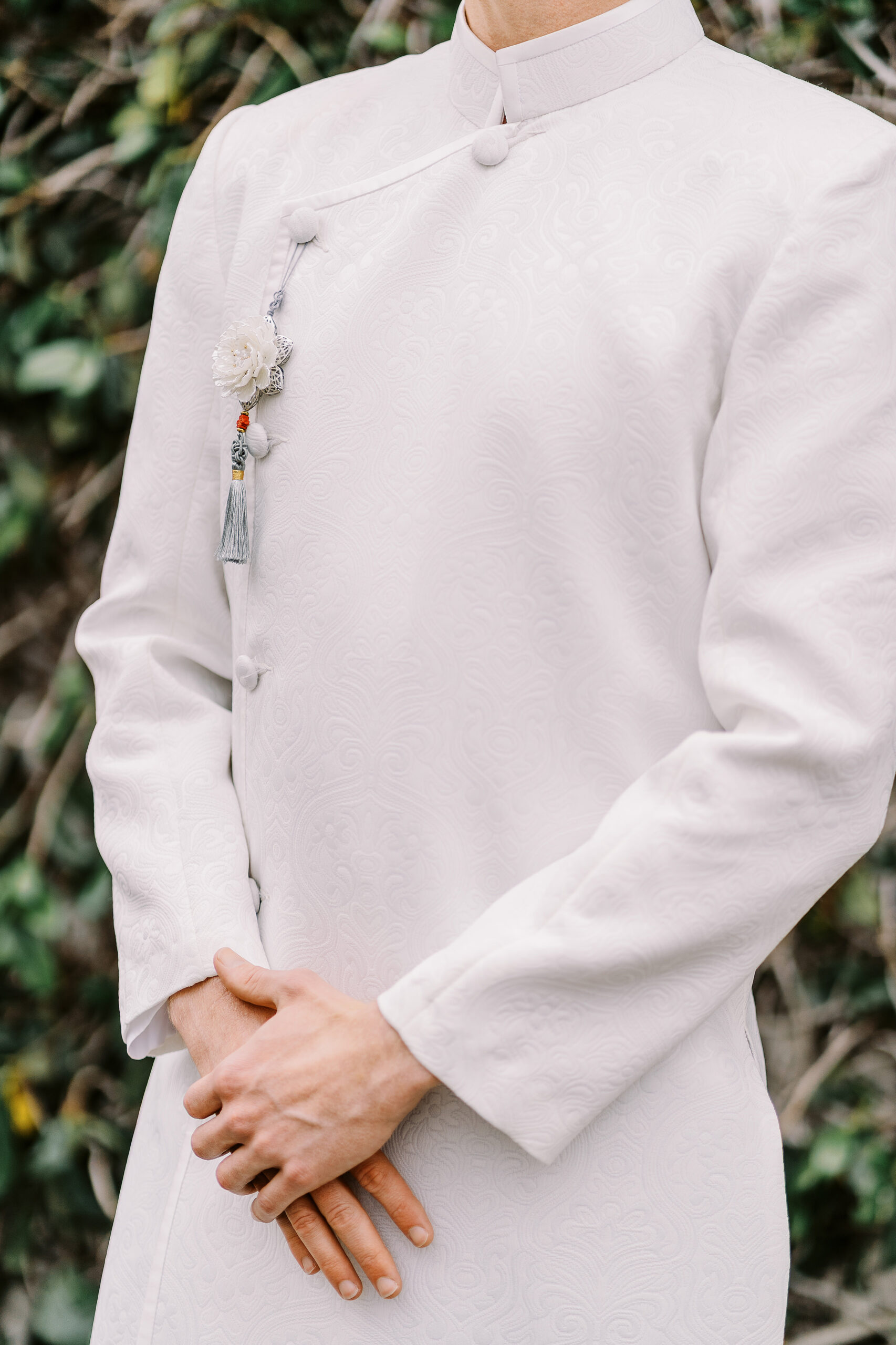 a close up photo of an all white grooms ao dai