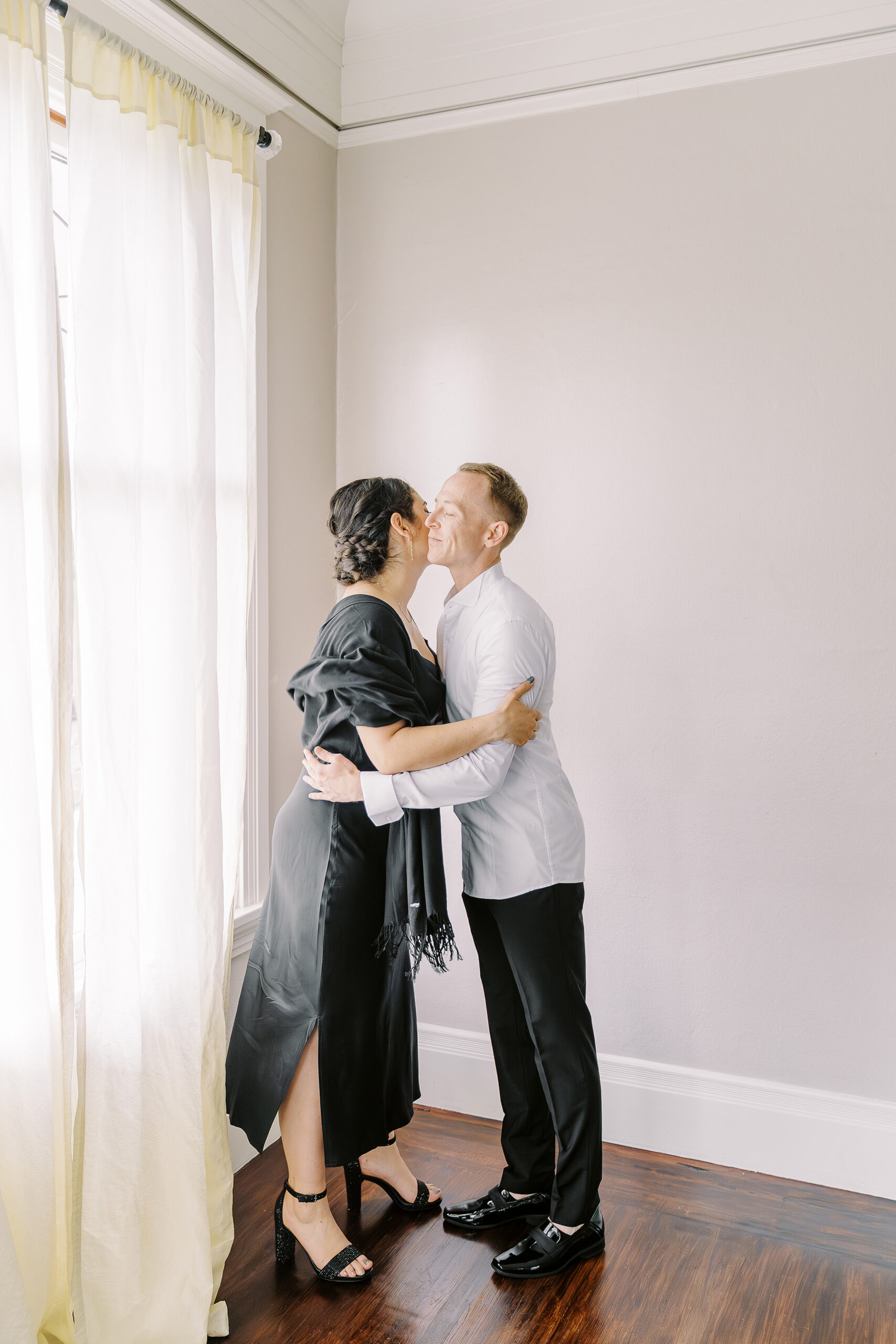 a groom hugs his friend while putting on his wedding attire at his Vizcaya Sacramento Wedding