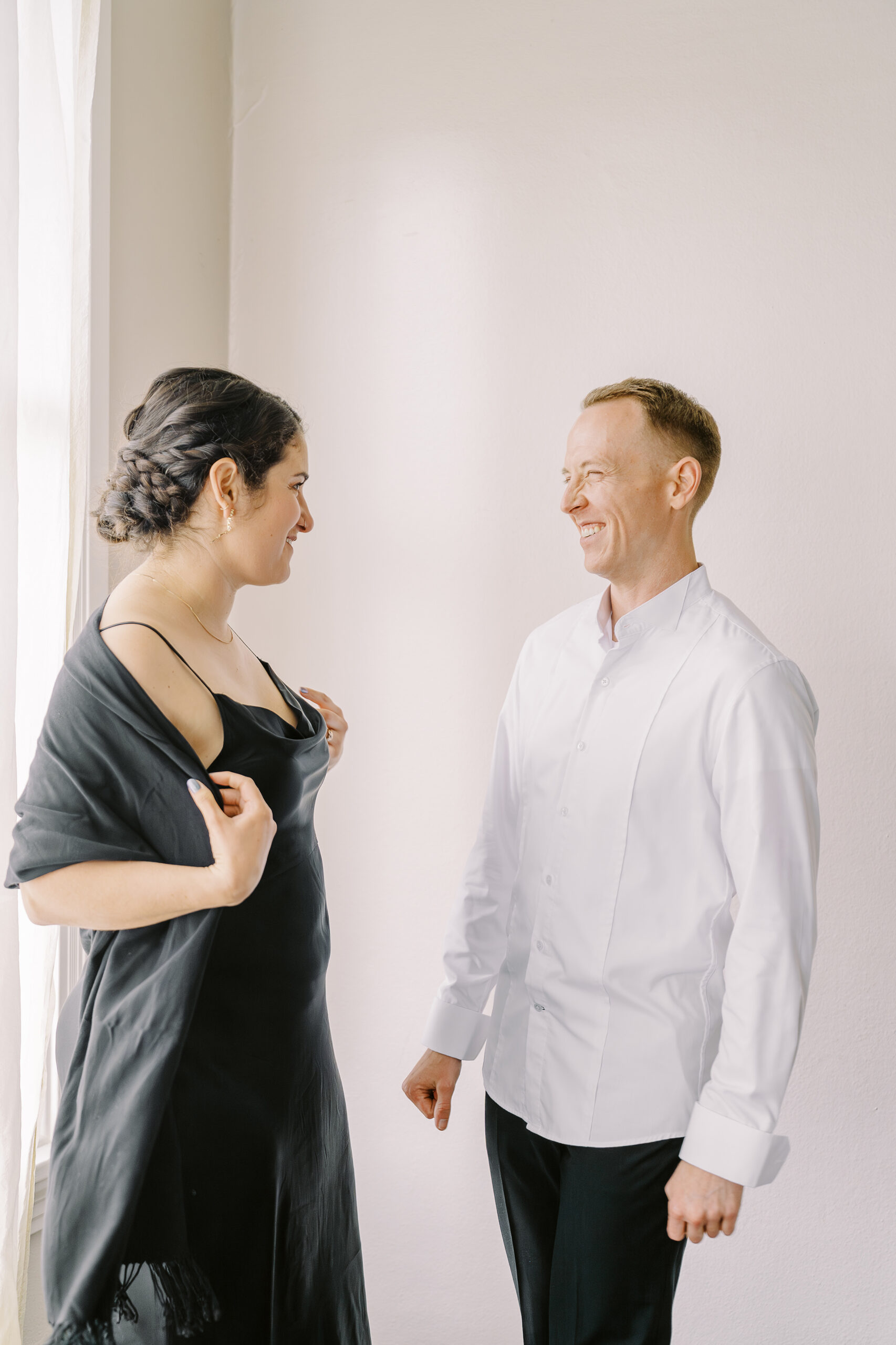 a groom laughs with his friend while putting on his wedding attire at his Vizcaya Sacramento Wedding