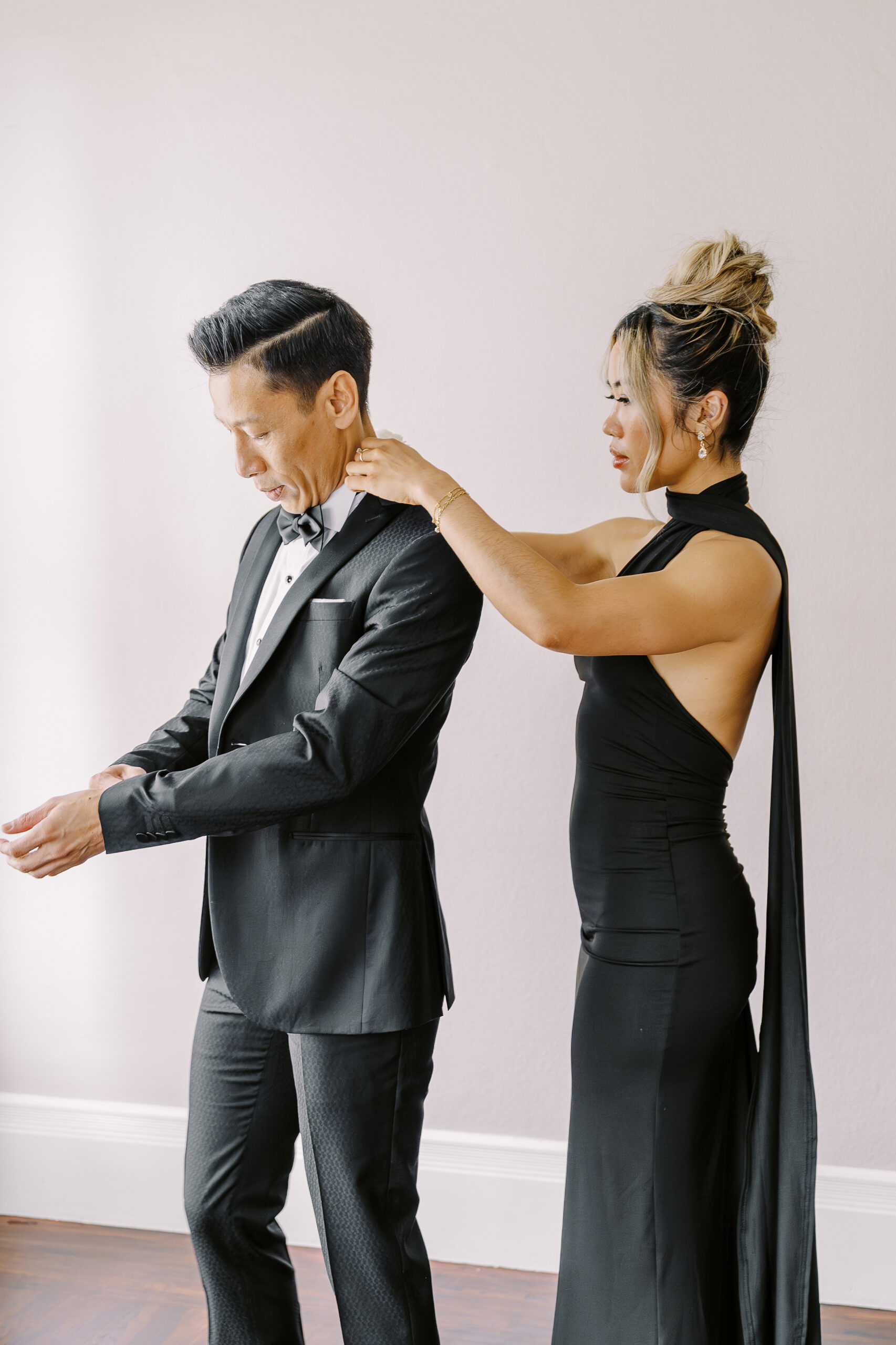 a grooms friend helps him straighten his shirt collar while getting ready for his vizcaya sacramento wedding