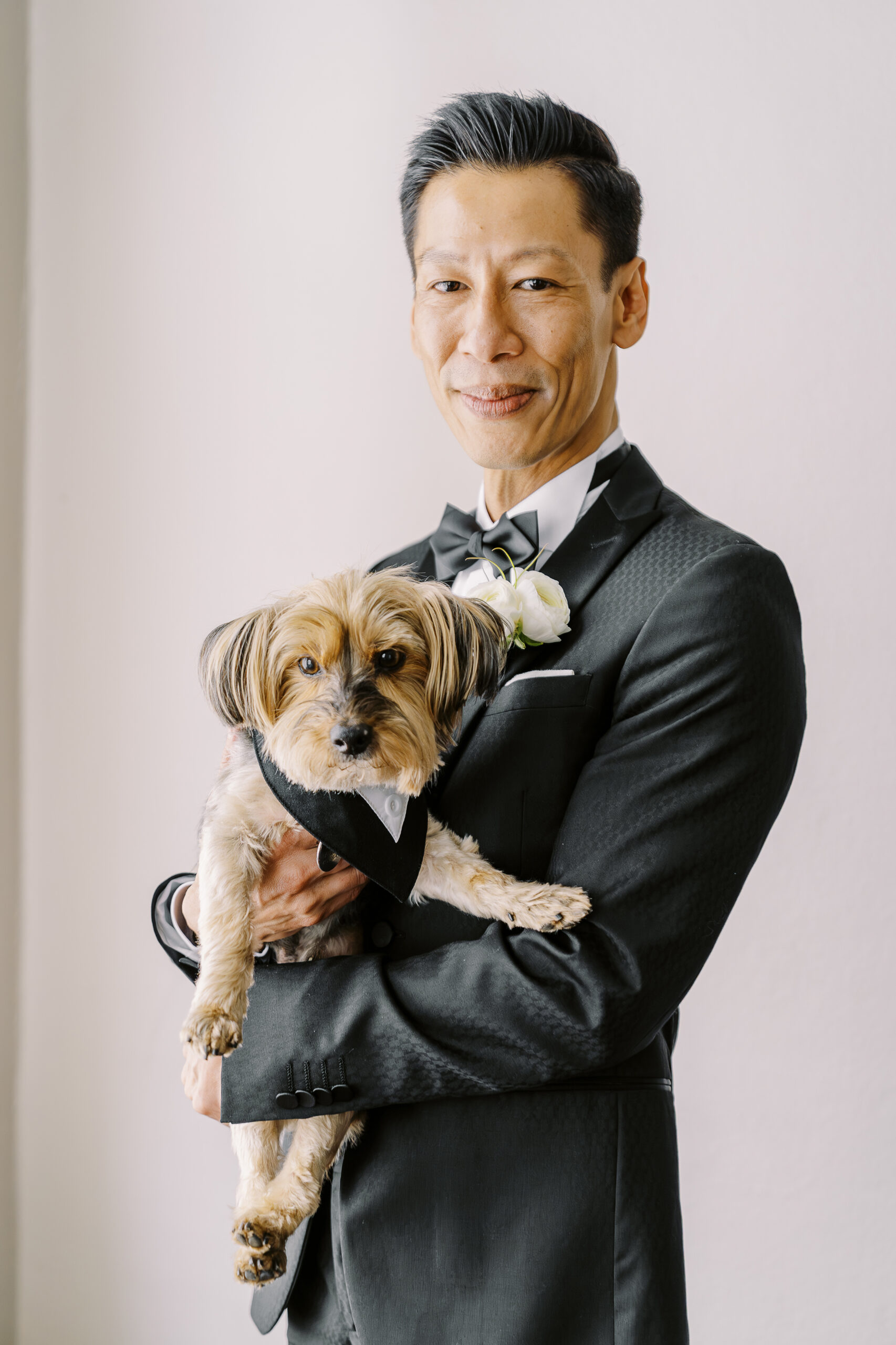 a groom poses for a portrait wile holding his dog at his vizcaya sacramento wedding