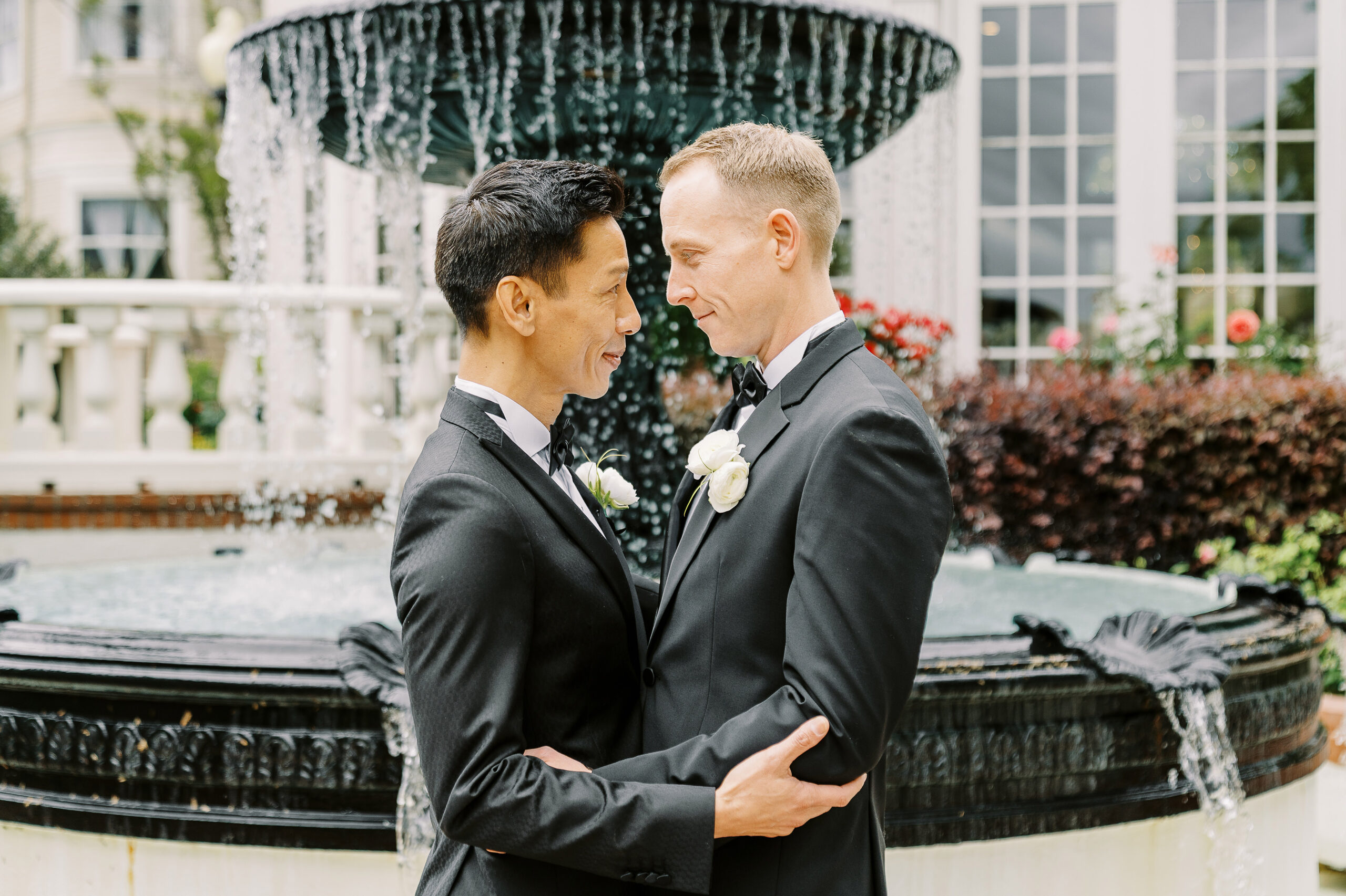 two groom embrace each other in front of the water fountain at their vizcaya sacramento wedding