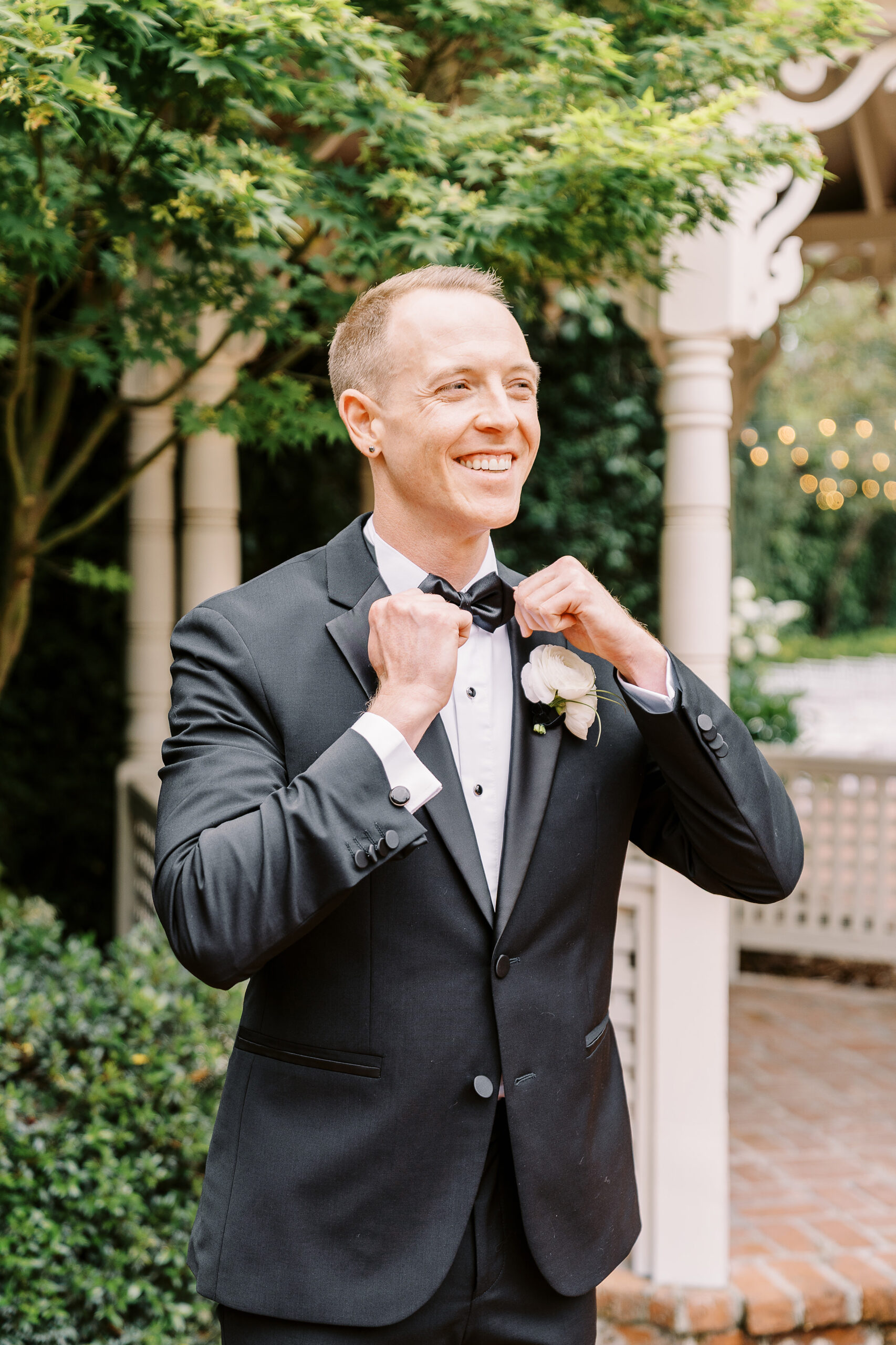 a groom straightens his bow tie during his vizcaya wedding