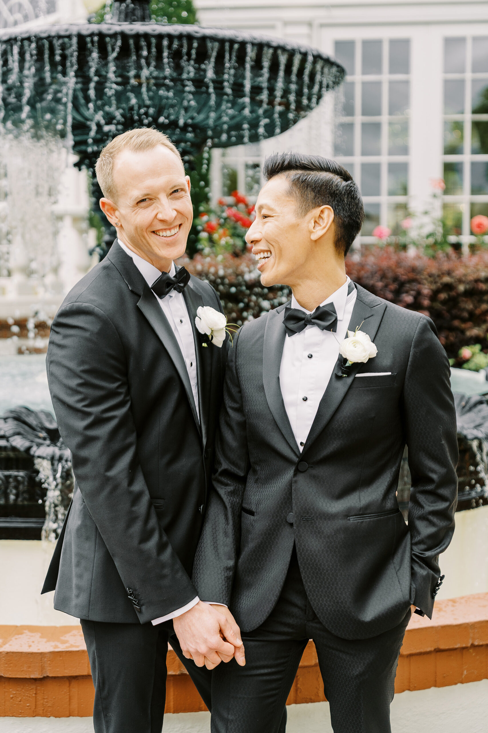two grooms share a laugh together in front of the vizcaya sacramento wedding venue fountain