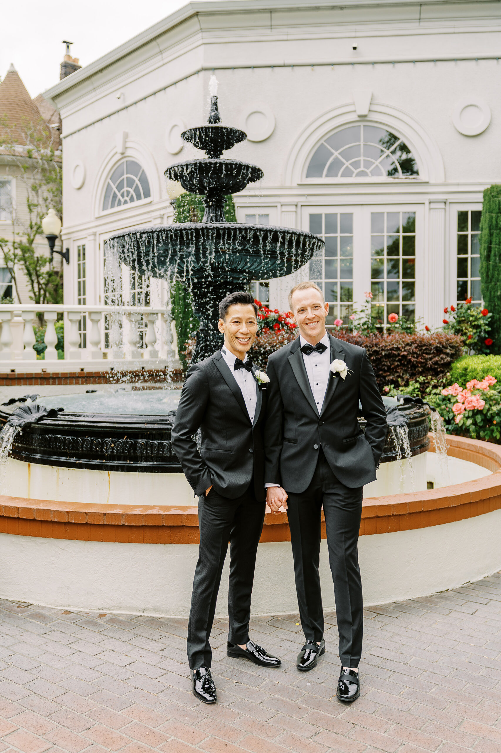 two grooms share a laugh together in front of the vizcaya sacramento wedding venue fountain