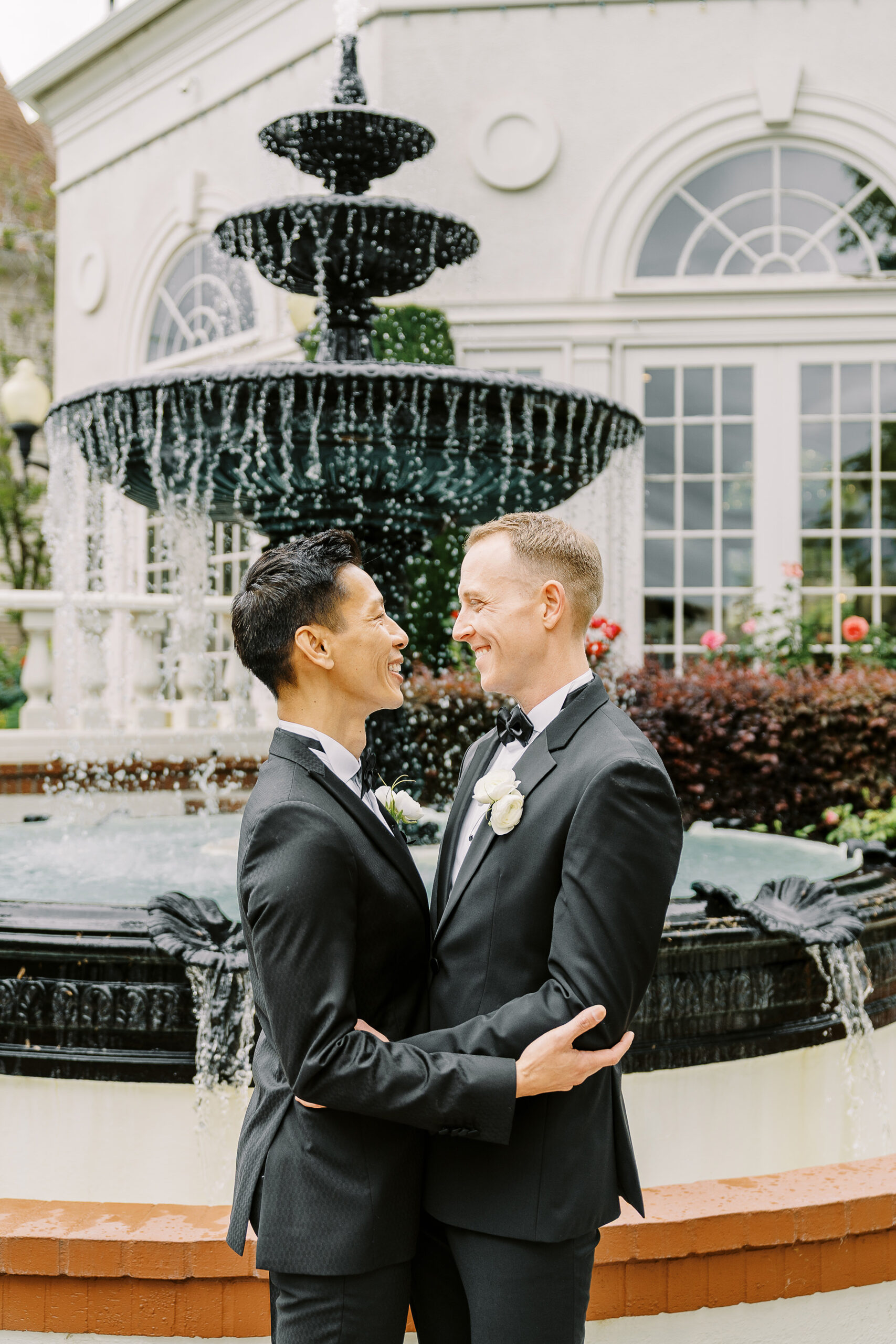 two grooms embrace each other in front of the water fountain at their vizcaya sacramento wedding