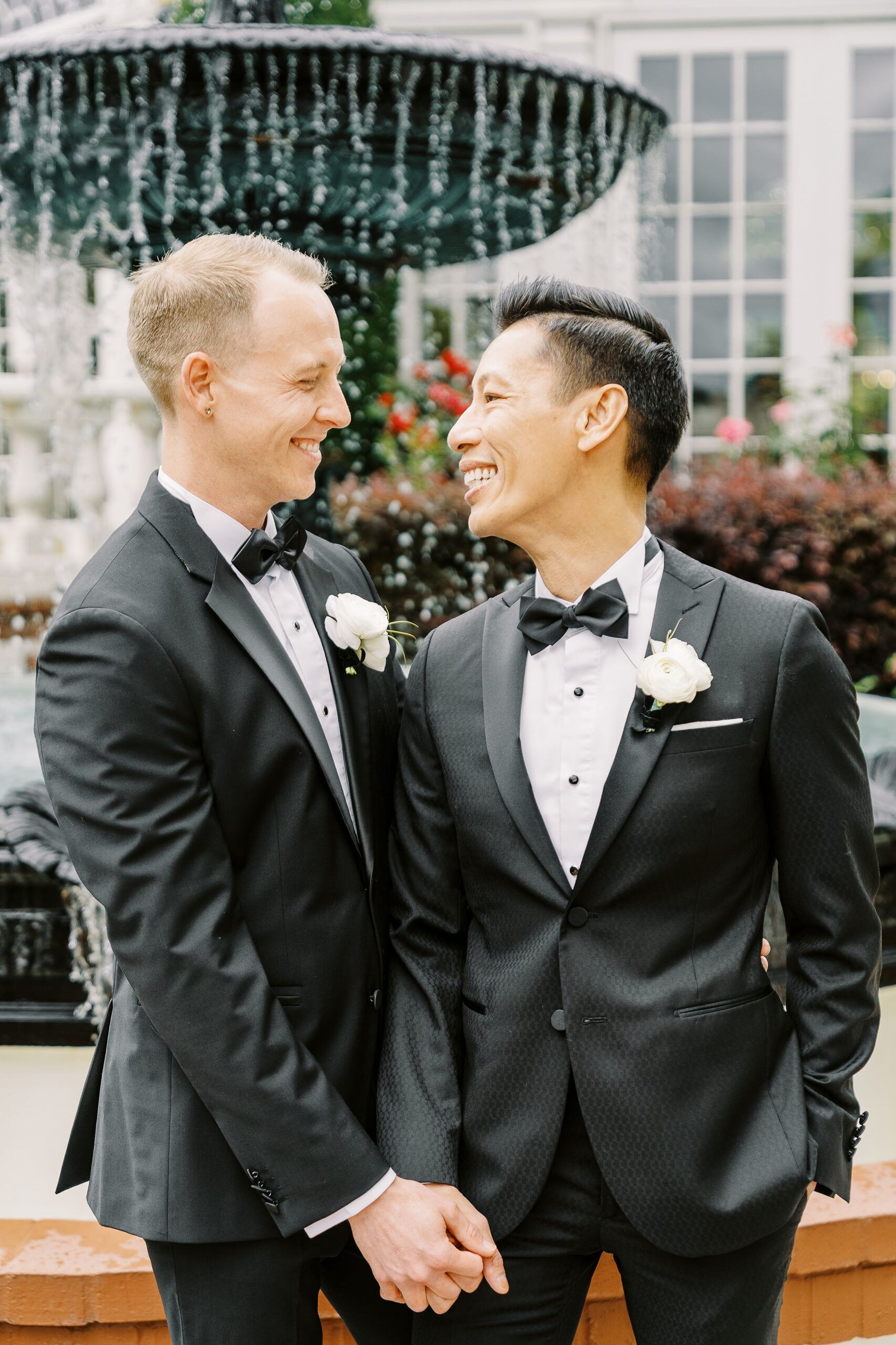 two grooms share a laugh together in front of the vizcaya sacramento wedding venue fountain