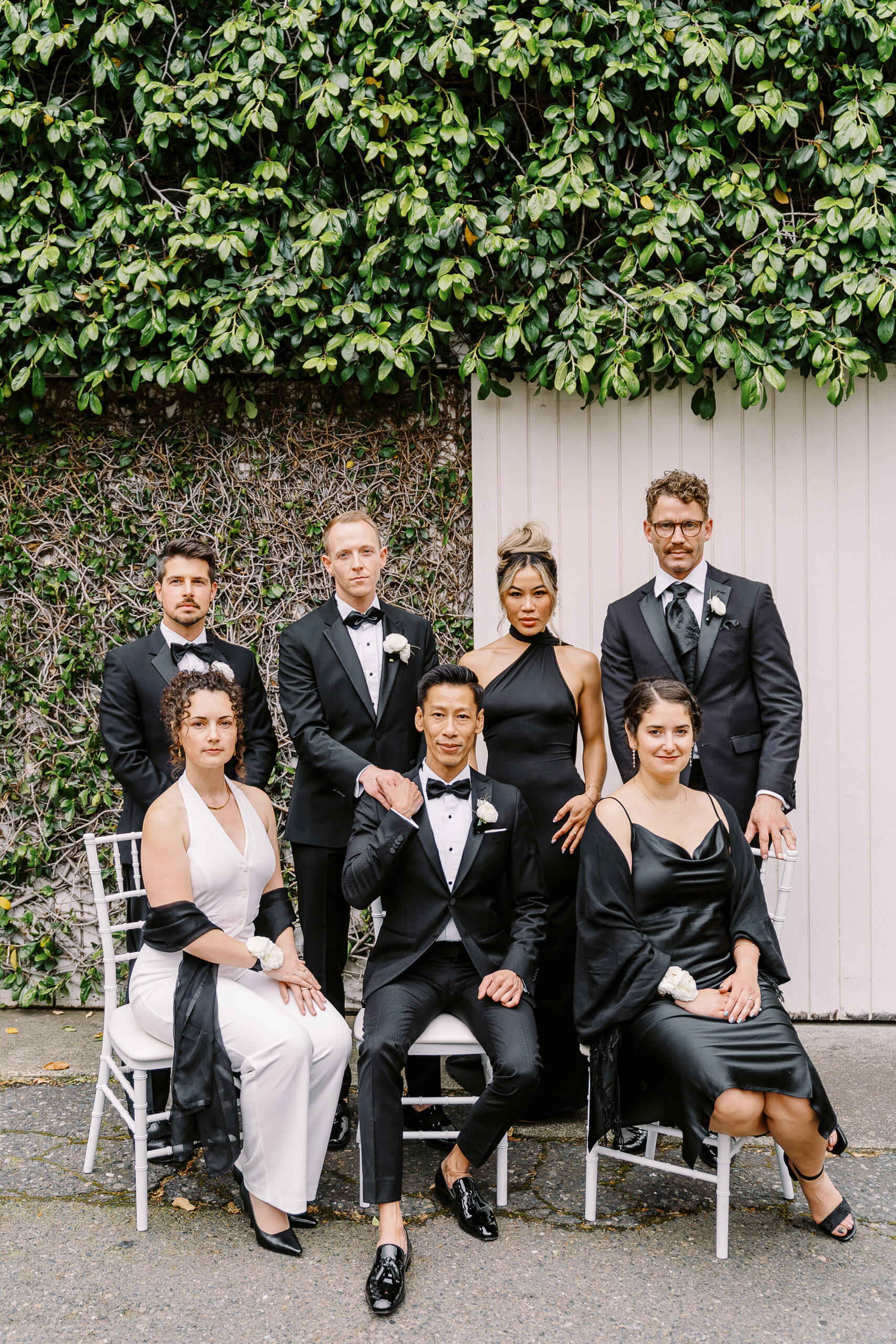 two grooms pose with their wedding party in sleek black tuxes at the vizcaya sacramento wedding venue