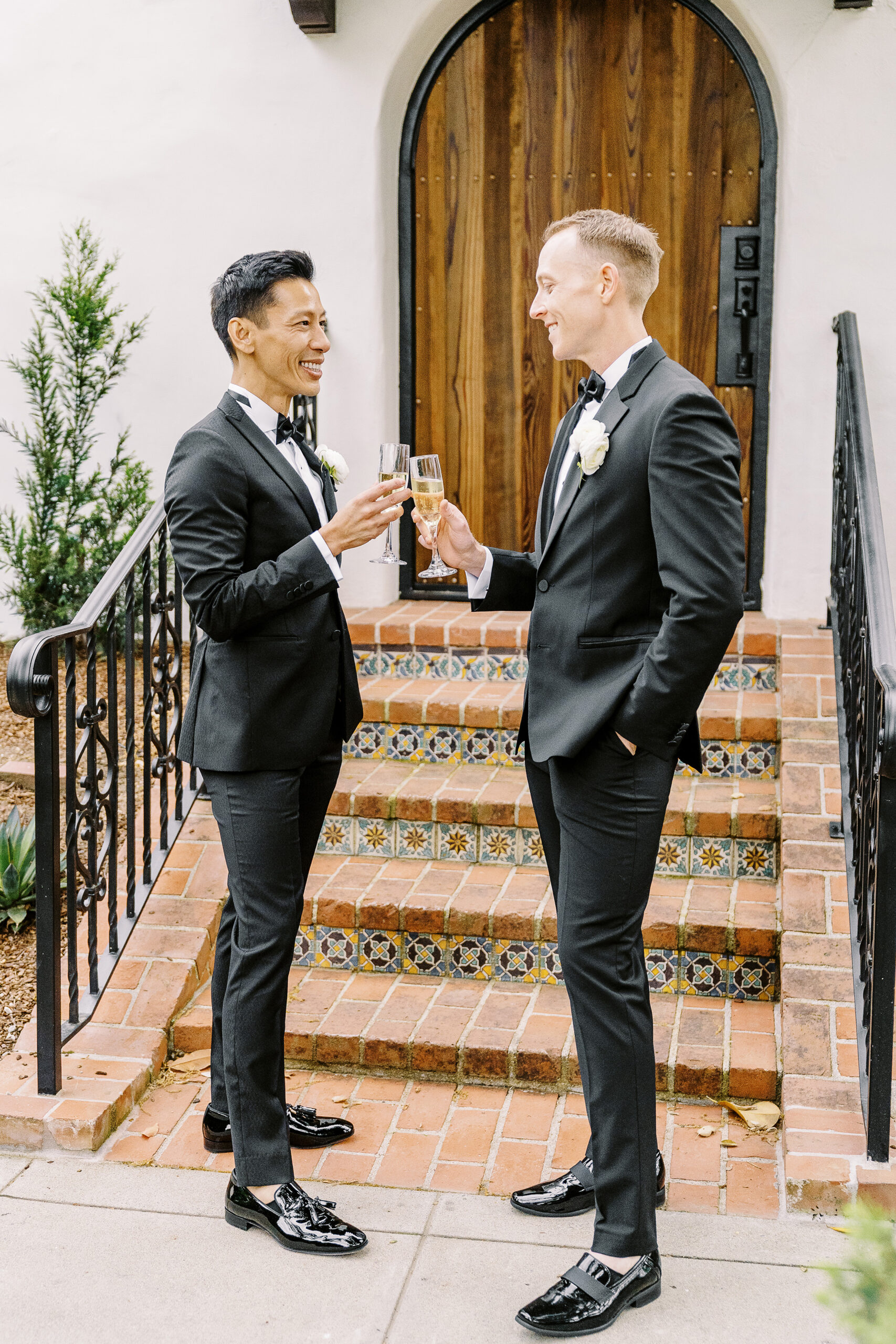 two grooms clink their champagne glasses in a toast at their vizcaya sacramento wedding