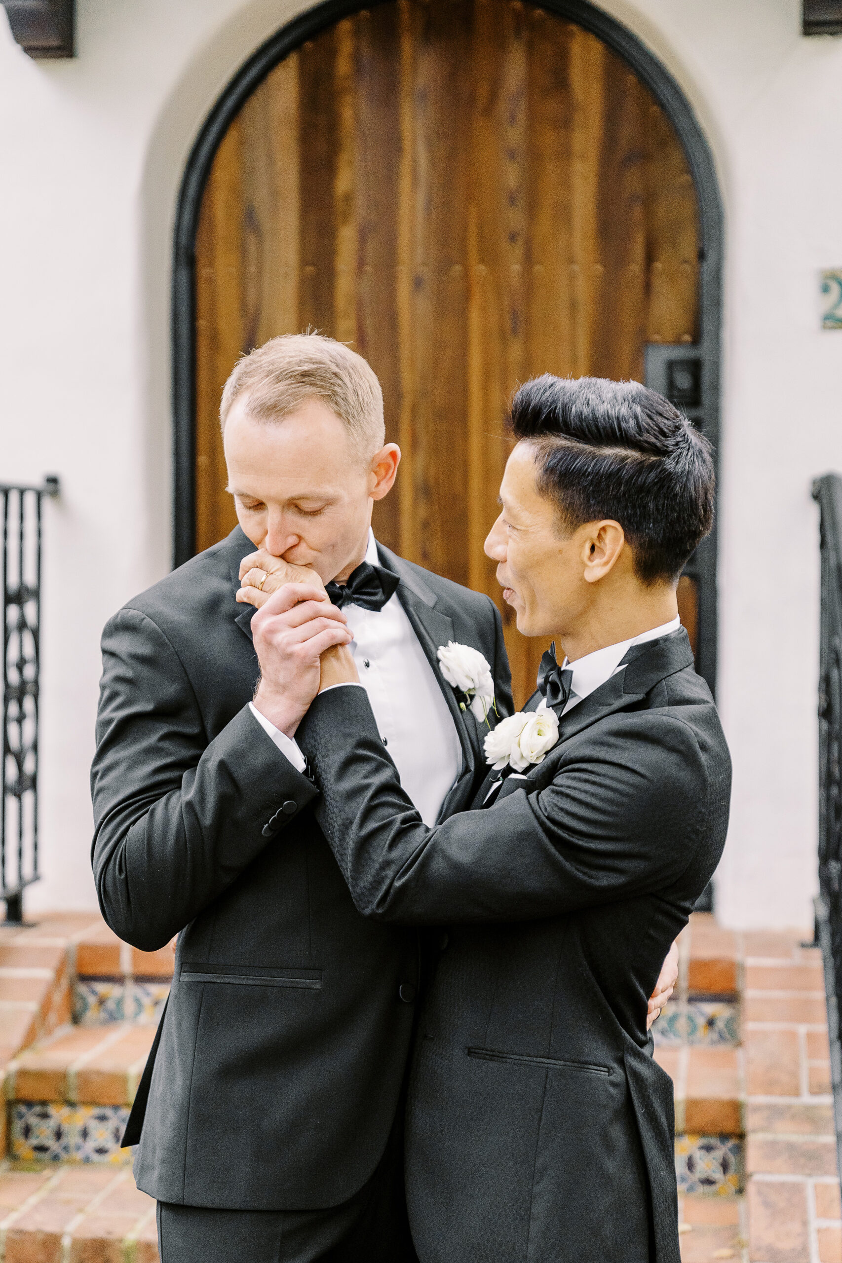 a groom kisses his new husbands hand during their vizcaya sacramento wedding