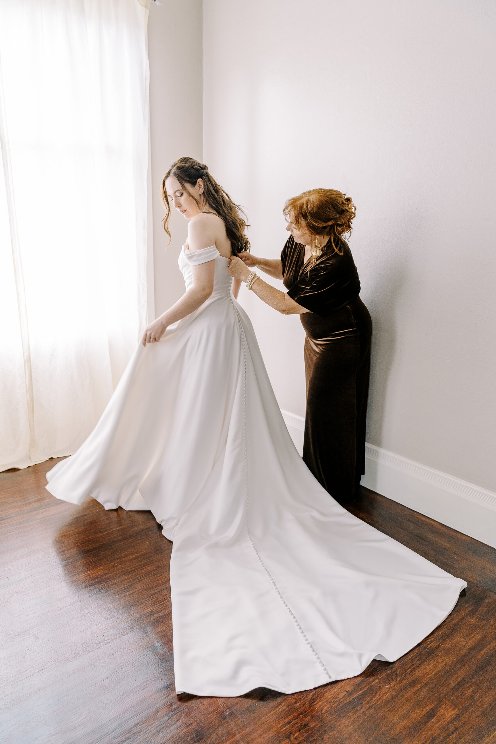 a brides mother helps her into her bridal gown at Vizcaya photographed by Sacramento wedding photographers