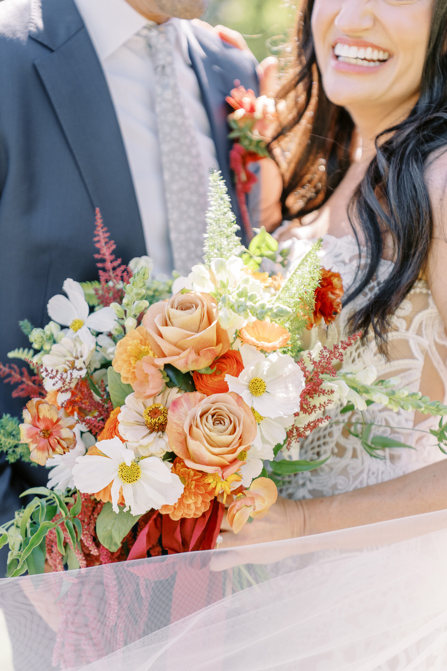 a bride holds her bouquet of orange and white flowers at her midtown Sacramento wedding photographed by Sacramento wedding photographer