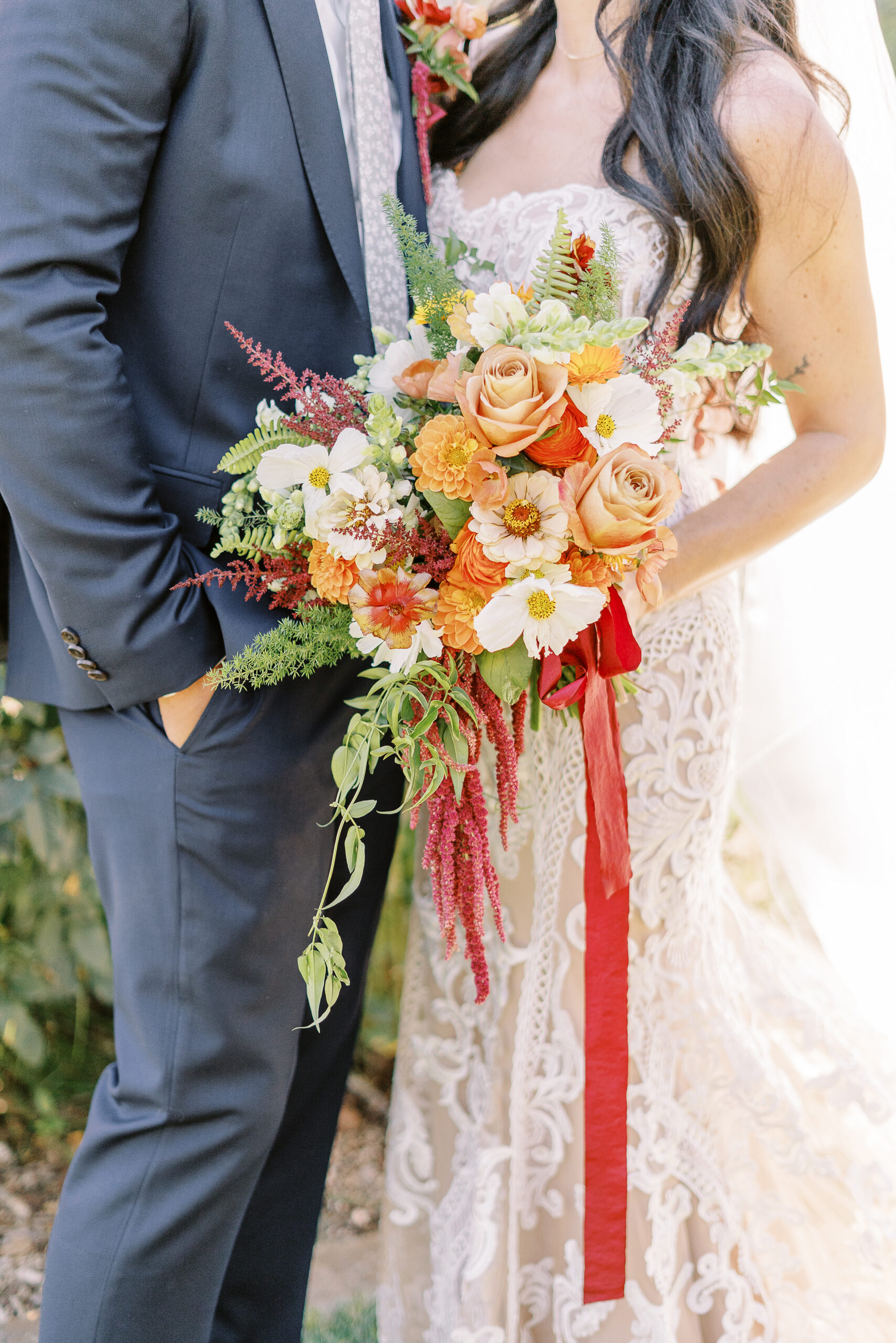 a bride holds her bouquet of orange and white flowers in the McKinley Park Rose Garden at her midtown Sacramento wedding photographed by Sacramento wedding photographer