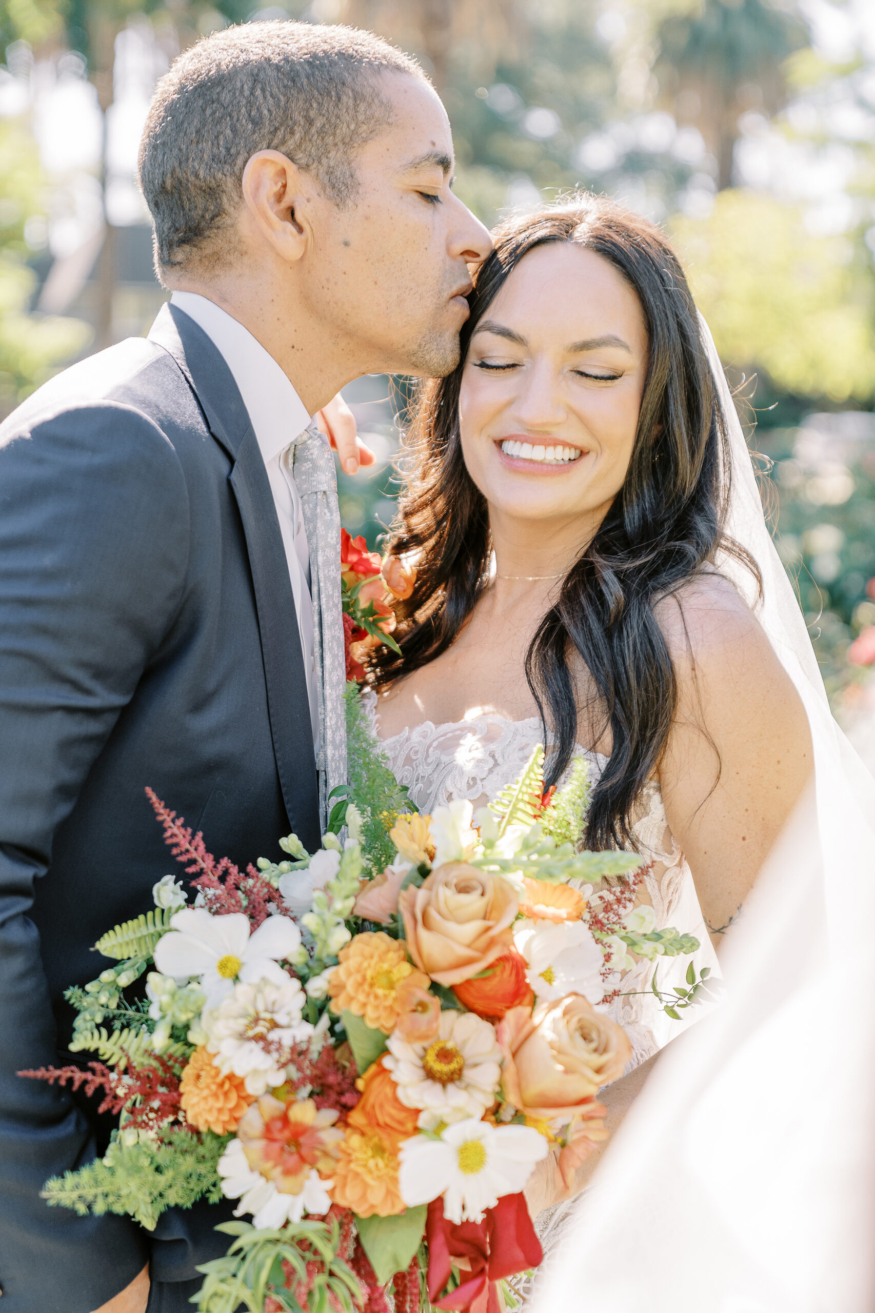 a groom kisses his bride on the forehead in the McKinley Park Rose Garden at their midtown Sacramento wedding photographed by Sacramento wedding photographer
