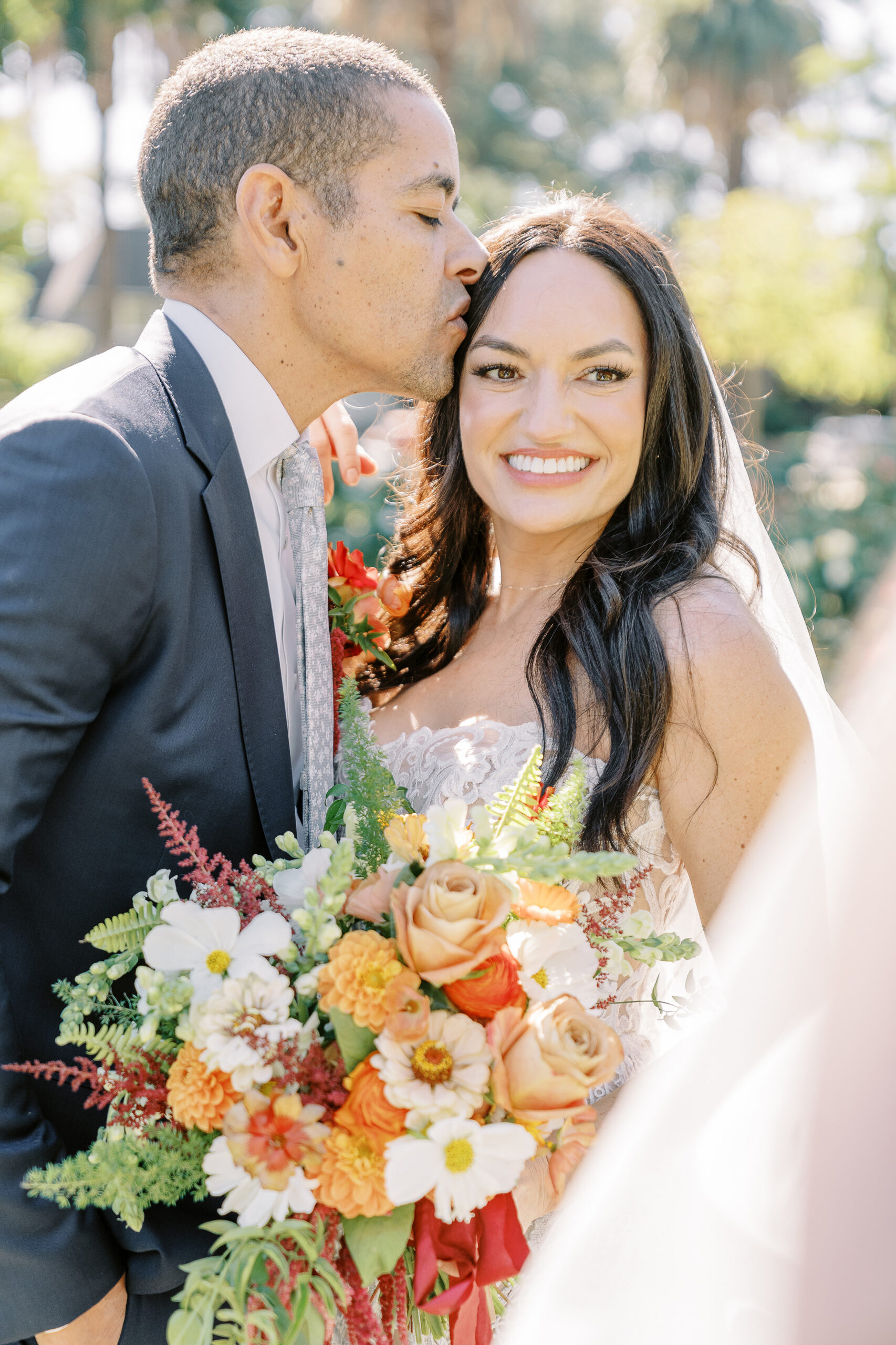 a groom kisses his bride on the forehead in the McKinley Park Rose Garden at their midtown Sacramento wedding photographed by Sacramento wedding photographer