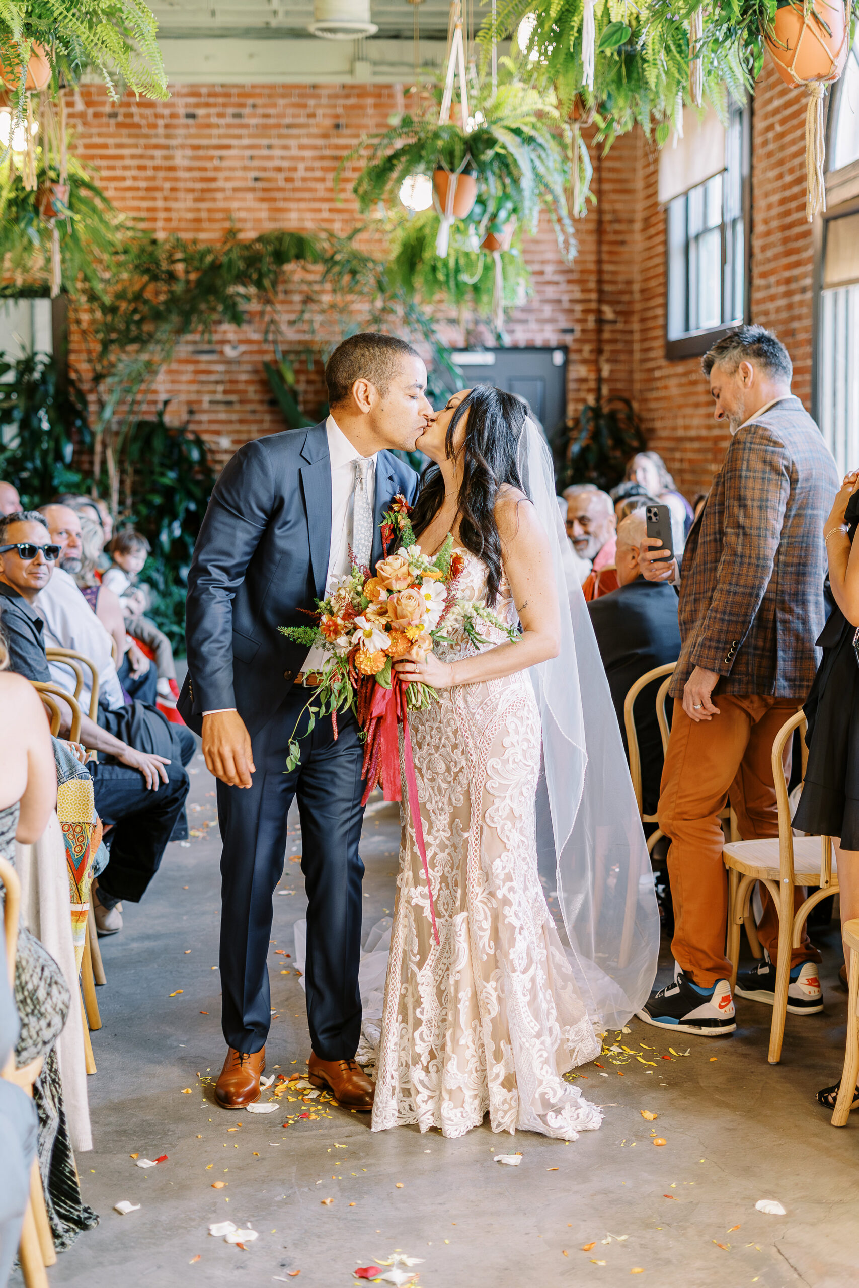 a bride and groom shares a kiss while walking down their aisle as husband and wife at their midtown Sacramento wedding ceremony photographed by Sacramento wedding photographer