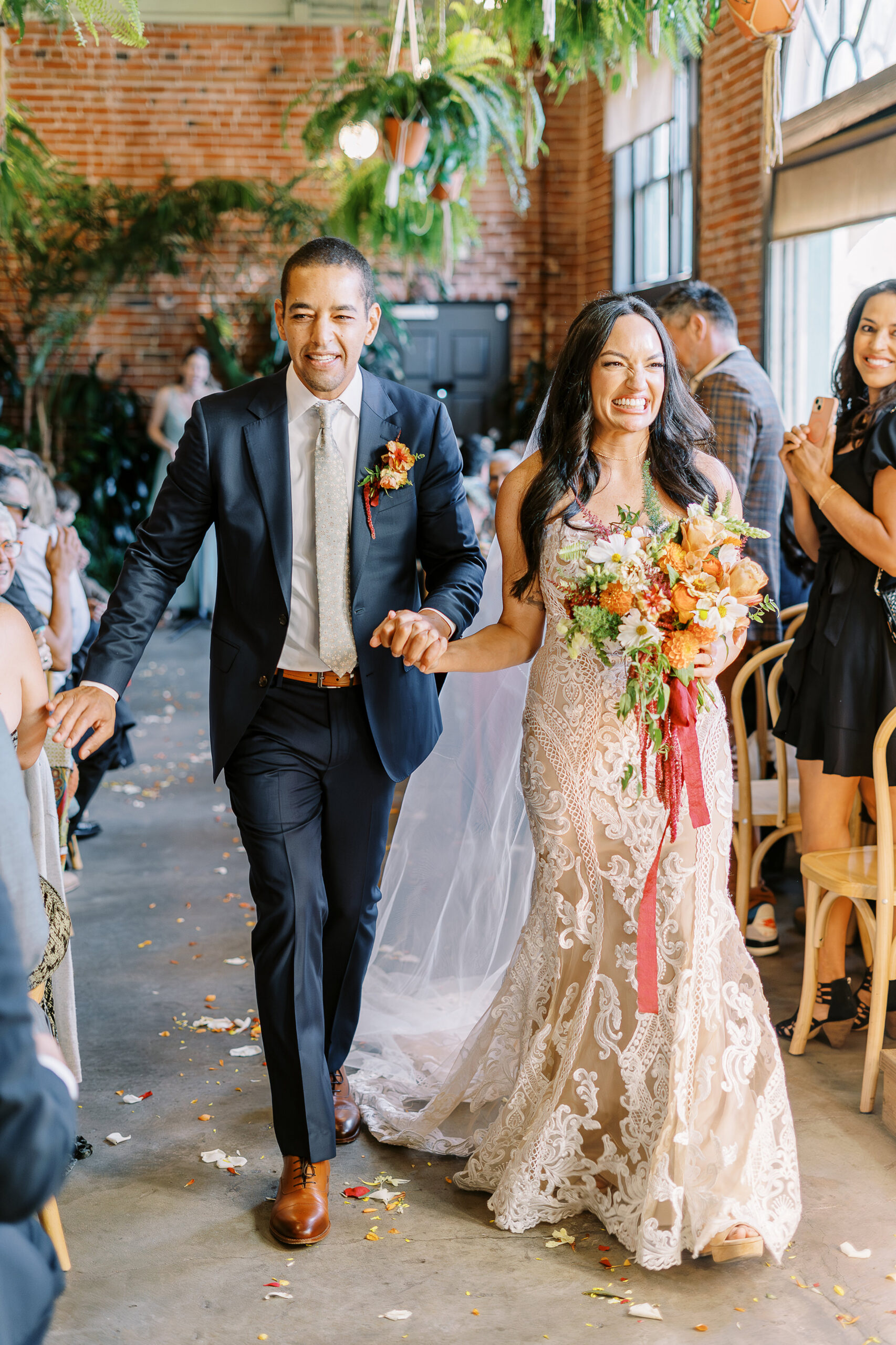 a bride and groom celebrate and laugh while walking down their aisle as husband and wife at their midtown Sacramento wedding ceremony photographed by Sacramento wedding photographer