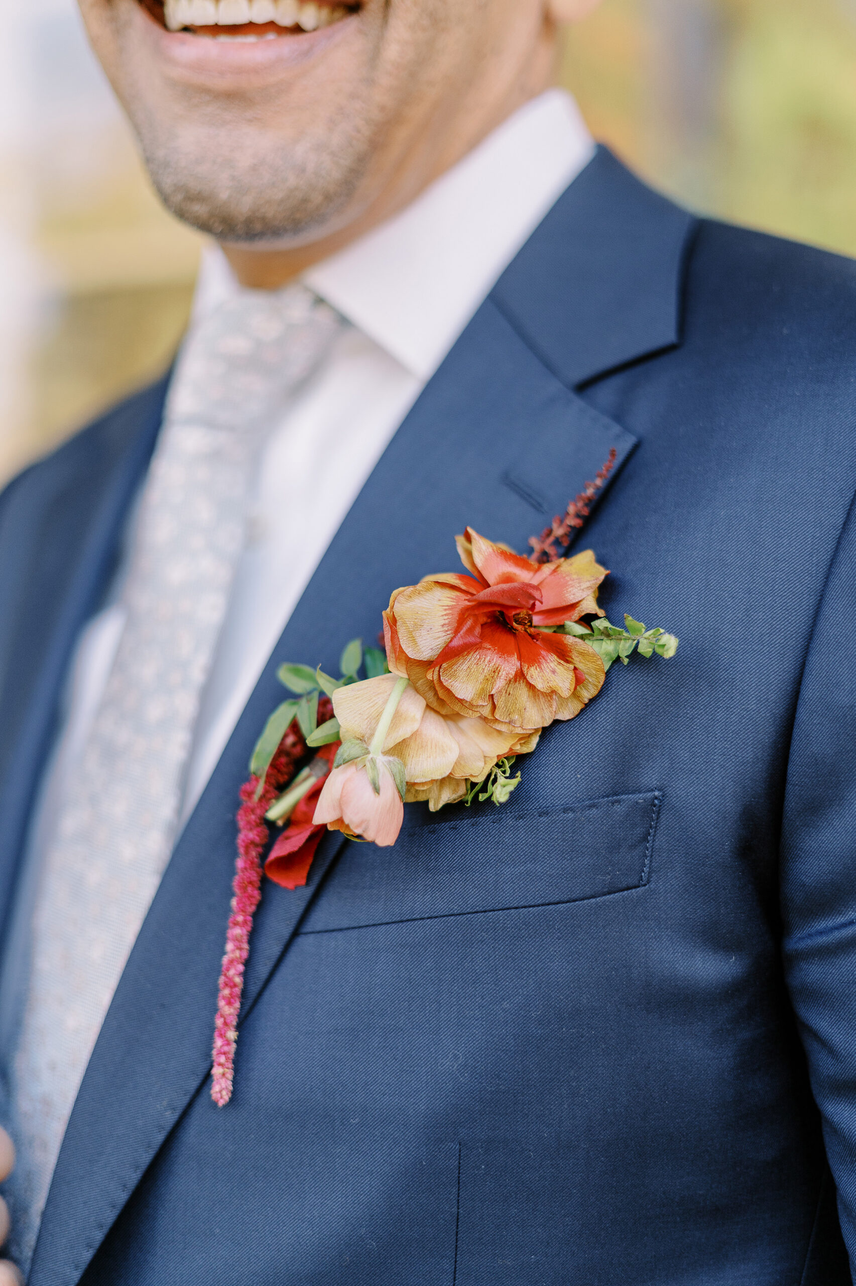 a groom shows off his boutonniere and blue suit at his midtown Sacramento wedding photographed by Sacramento wedding photographer