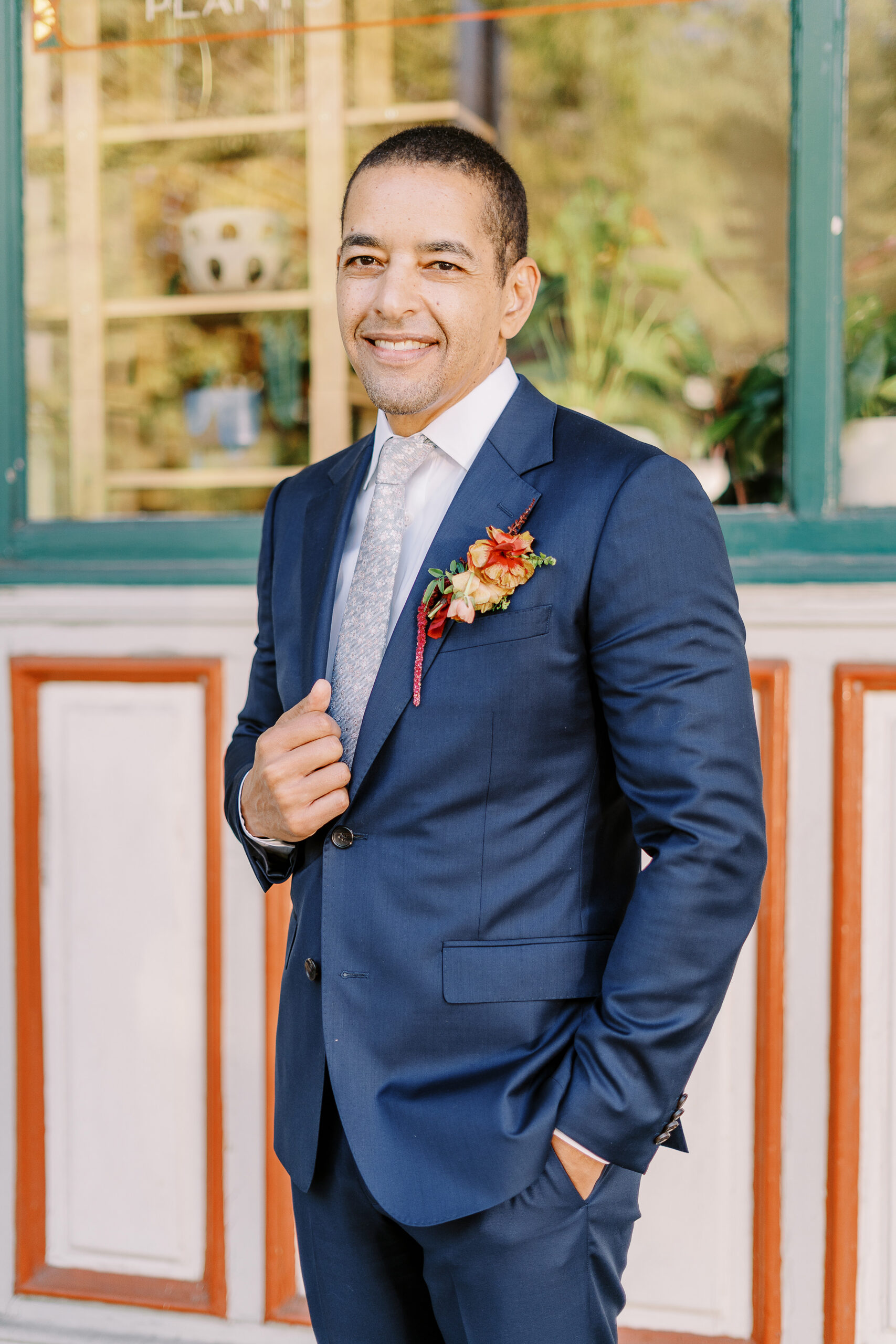 a groom shows off his boutonniere and blue suit at his midtown Sacramento wedding photographed by Sacramento wedding photographer