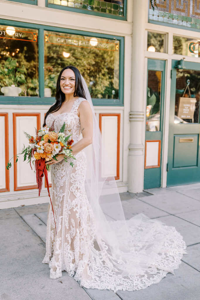 a bride holds her bouquet of orange and white flowers and laughs at her midtown Sacramento wedding photographed by Sacramento wedding photographer