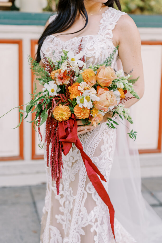 a bride holds her bouquet of orange and white flowers at her midtown Sacramento wedding photographed by Sacramento wedding photographer
