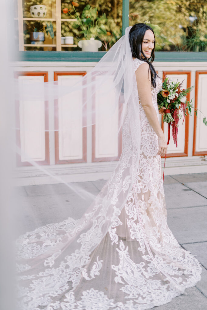 a bride holds her bouquet of orange and white flowers and laughs at her midtown Sacramento wedding photographed by Sacramento wedding photographer