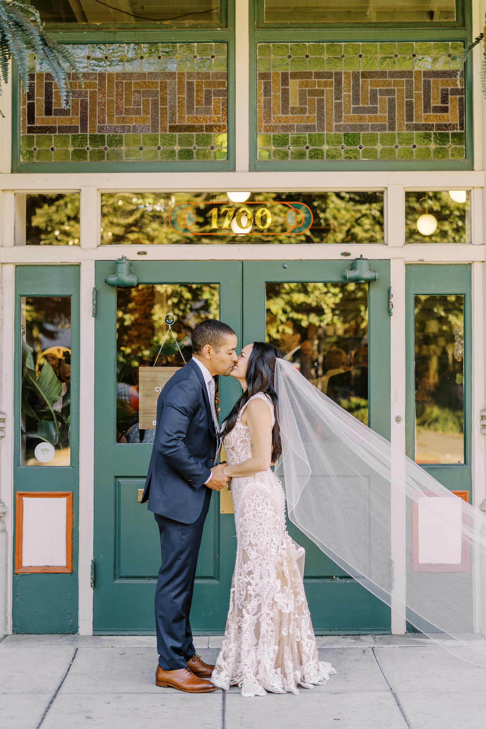 a bride and groom hold hands and share a kiss at their midtown Sacramento wedding photographed by Sacramento wedding photographer