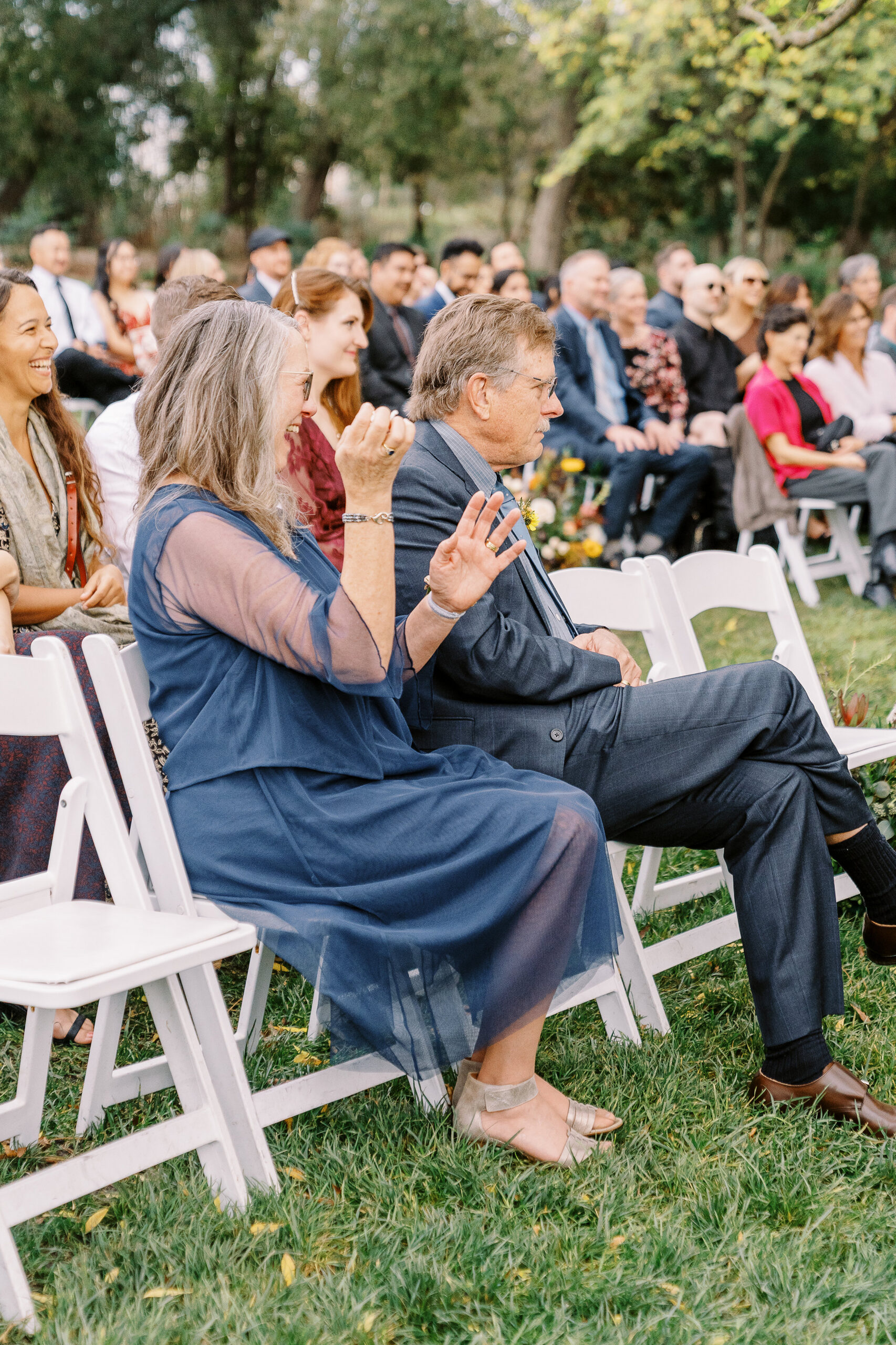 the mother of the groom claps and laughs at a ceremony at The Maples Woodland photographed by Sacramento wedding photographer