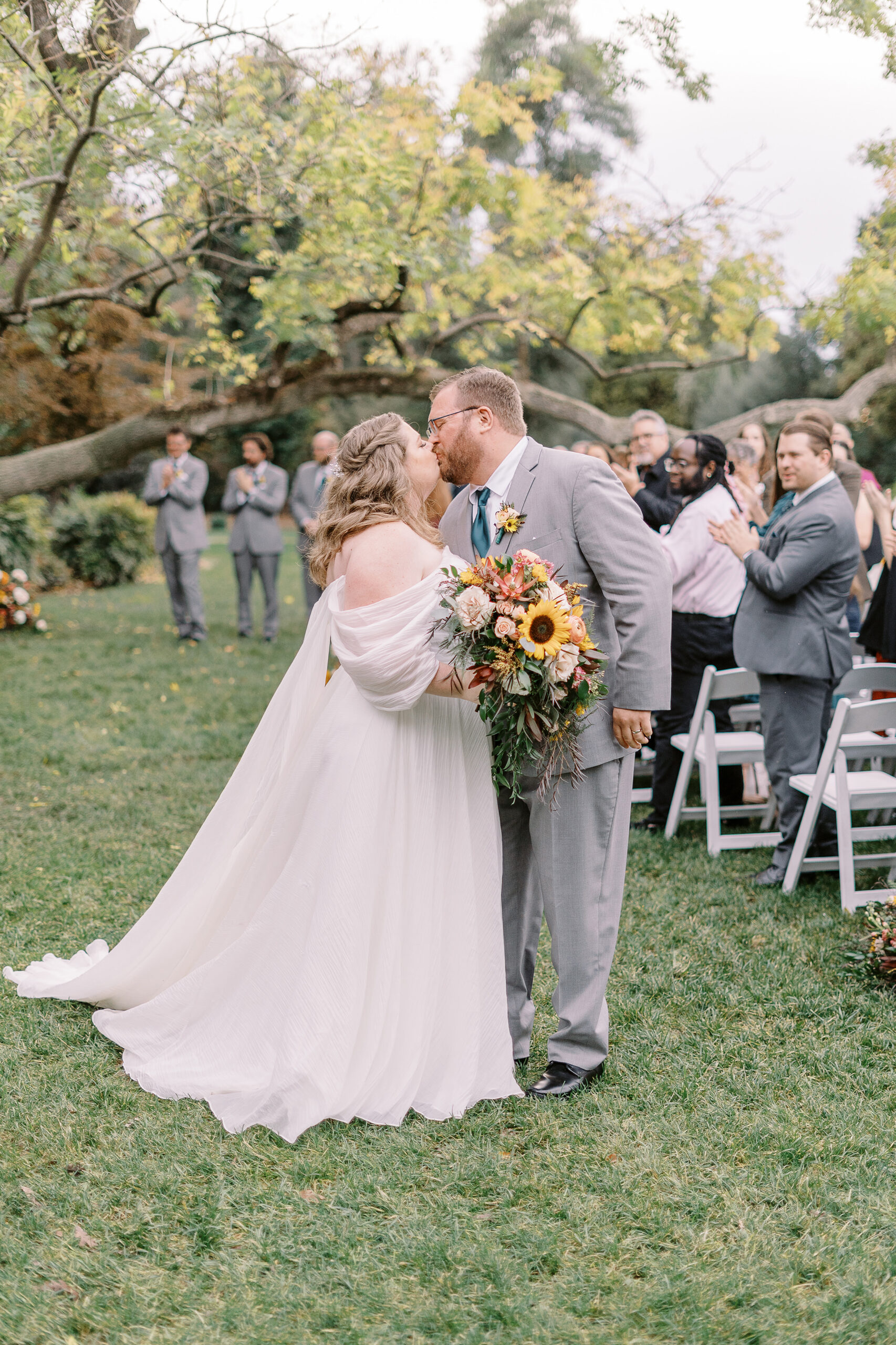 a bride and groom share a kiss while walking down the aisle at a ceremony at The Maples Woodland photographed by Sacramento wedding photographer
