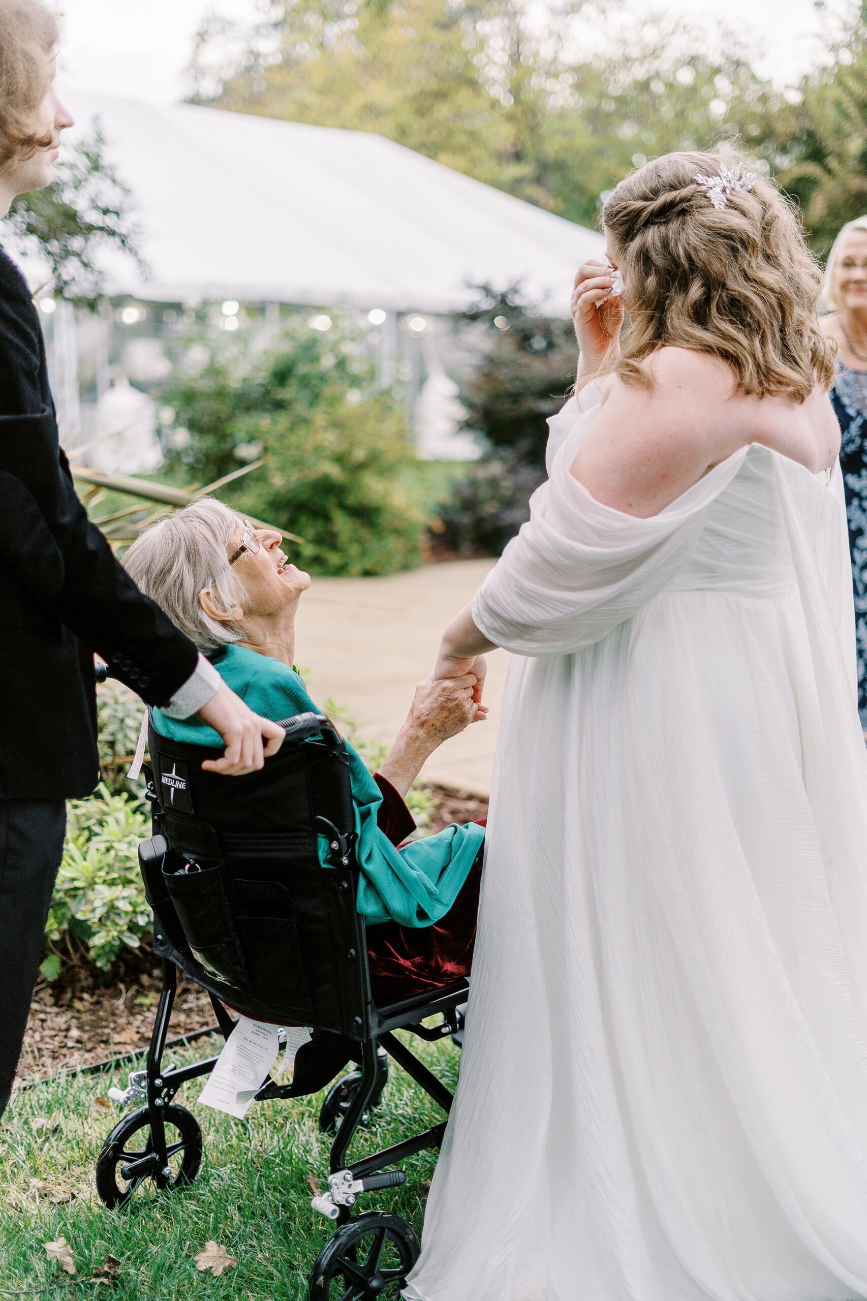 the brides grandmother holds the brides hand as the bride wipes away a tear at The Maples Woodland photographed by Sacramento wedding photographer