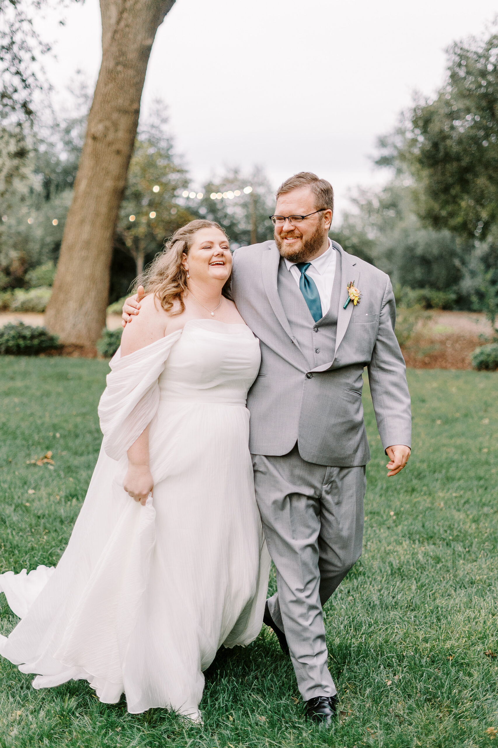 a groom puts his arm around his bride as they laugh and walk together at The Maples Woodland photographed by Sacramento wedding photographer