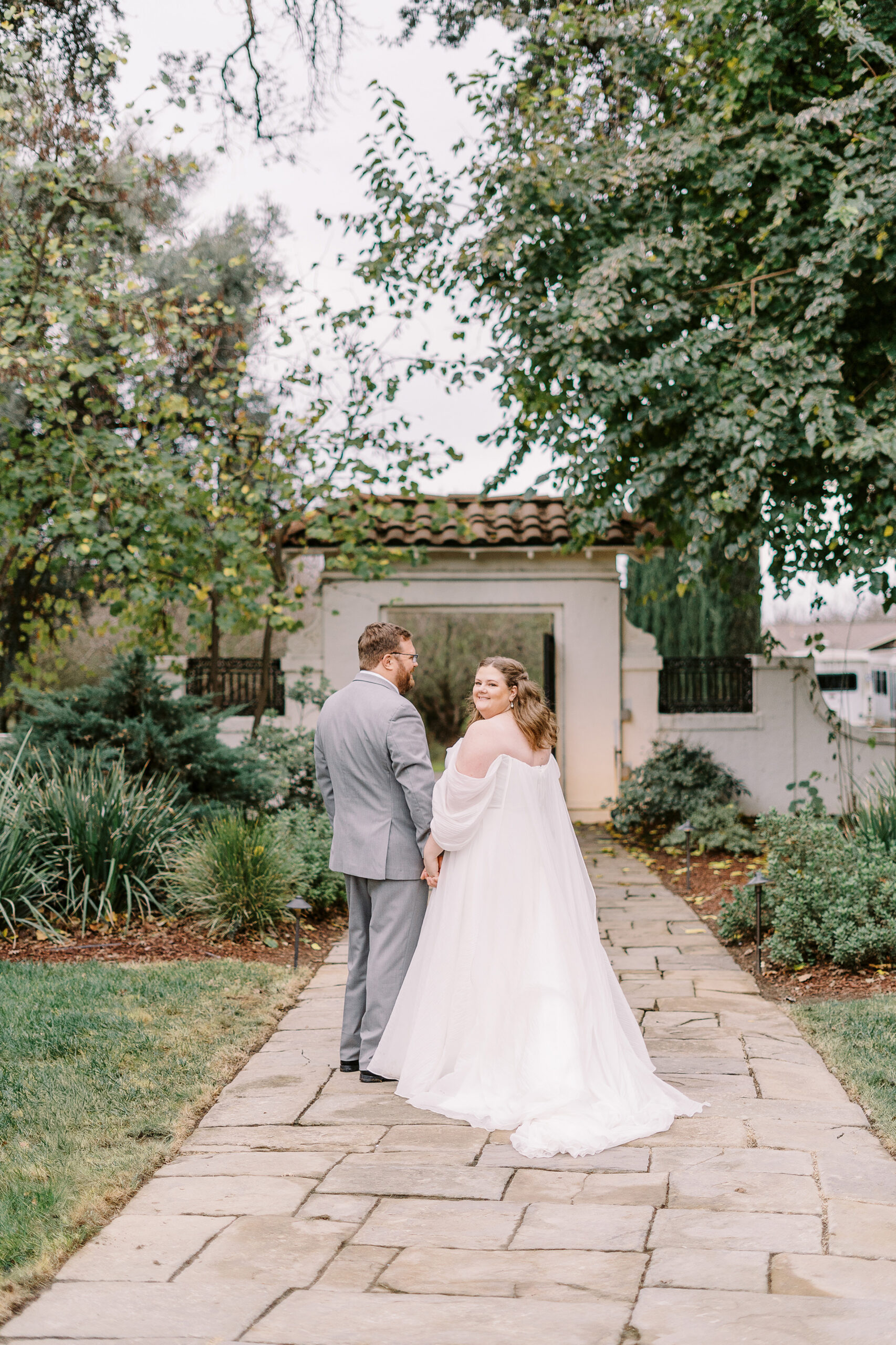 a bride and groom pose for a portrait in front of the gate at The Maples Woodland photographed by Sacramento wedding photographer